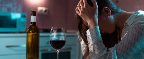 женщина с алкогольной зависимостью сидит за столом